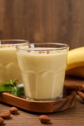 Photo of Tasty banana smoothie with almond and cinnamon on wooden table