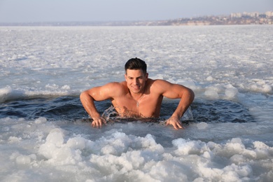 Photo of Man immersing in icy water on winter day. Baptism ritual