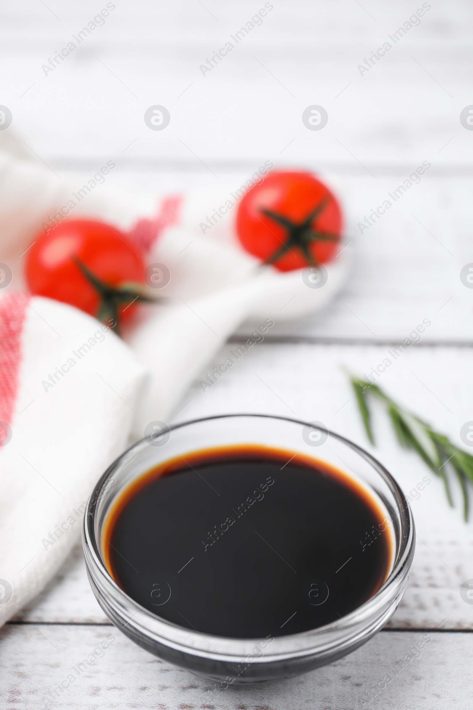 Photo of Bowl with balsamic vinegar and tomatoes on white wooden table. Space for text