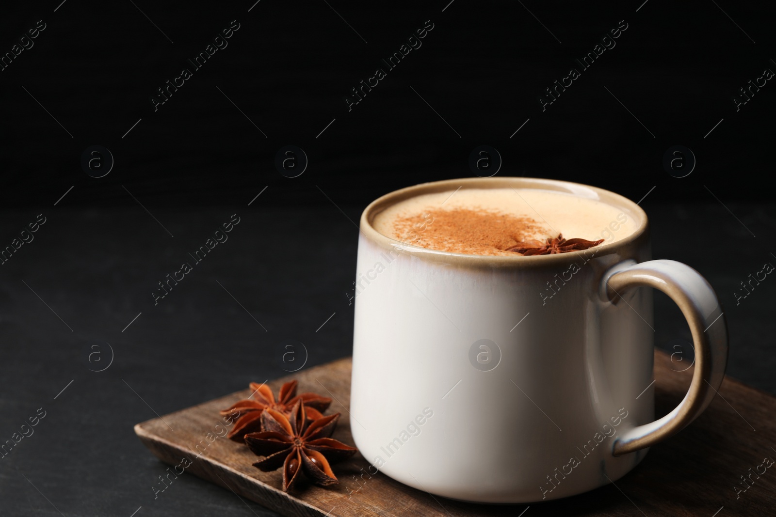 Photo of Delicious eggnog with anise and cinnamon on black table, closeup. Space for text