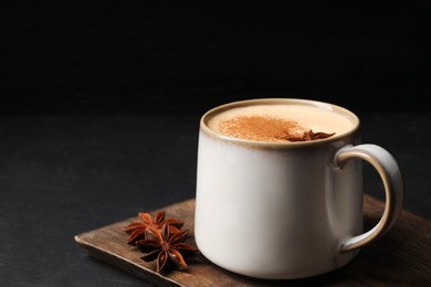 Photo of Delicious eggnog with anise and cinnamon on black table, closeup. Space for text