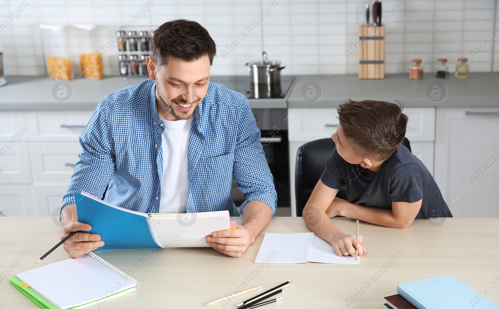 Photo of Dad helping his son with homework in kitchen