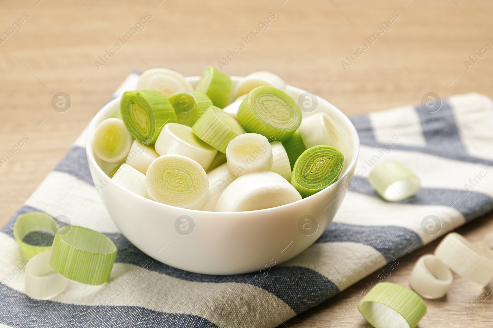 Photo of Cut fresh raw leek on wooden table, closeup