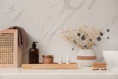 Photo of Personal hygiene products and toiletries on table near white wall in bathroom