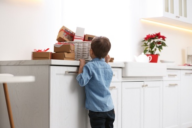 Photo of Little boy with Christmas gifts at home. Advent calendar in basket