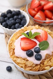 Delicious crispy cornflakes, yogurt and fresh berries in bowl on white wooden table, closeup. Healthy breakfast