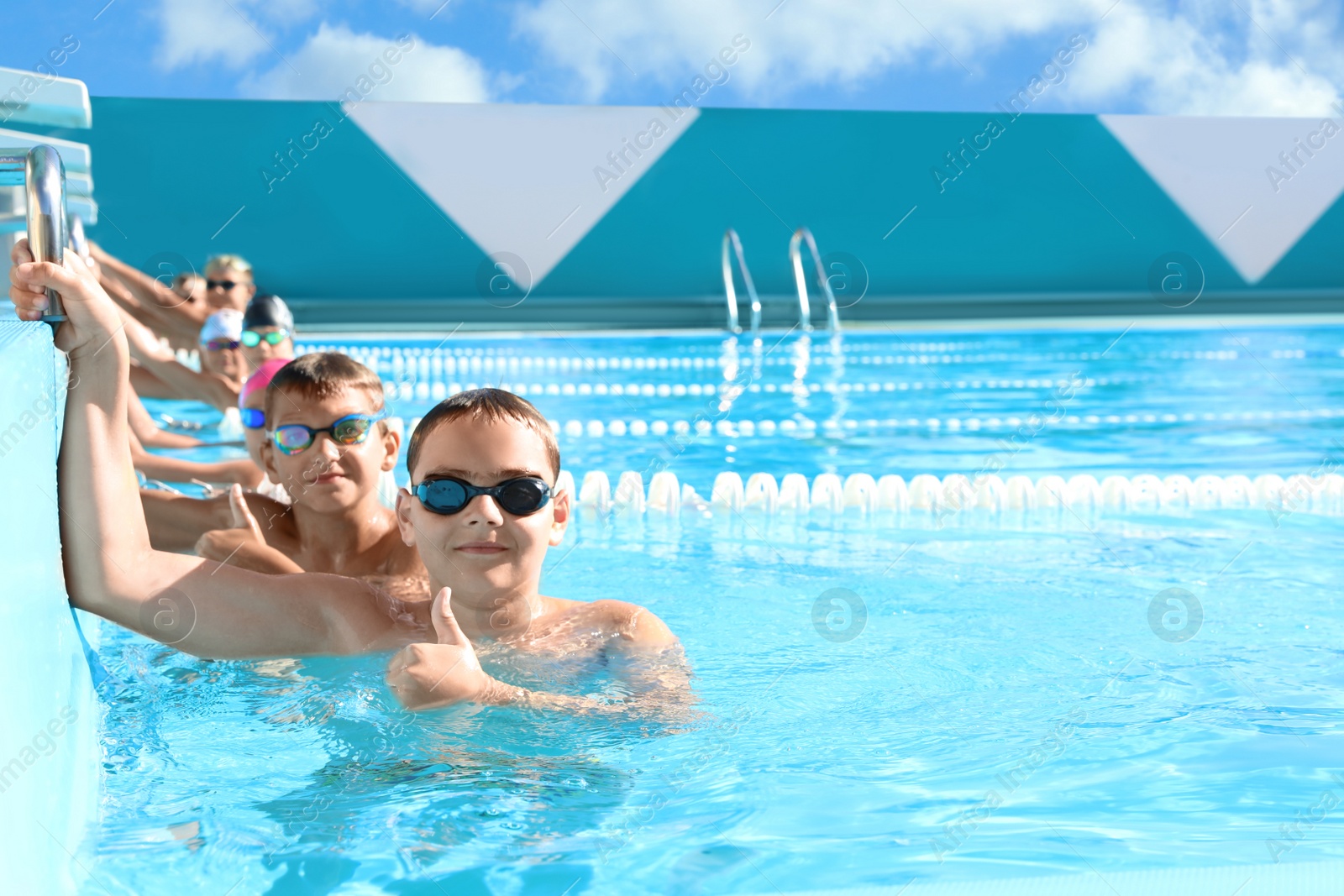 Photo of OCHAKIV, UKRAINE - JULY 09, 2020: Group of children in outdoor swimming pool on sunny day. Summer camp "Sportium"