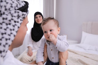 Photo of Happy Muslim family with little son in bedroom