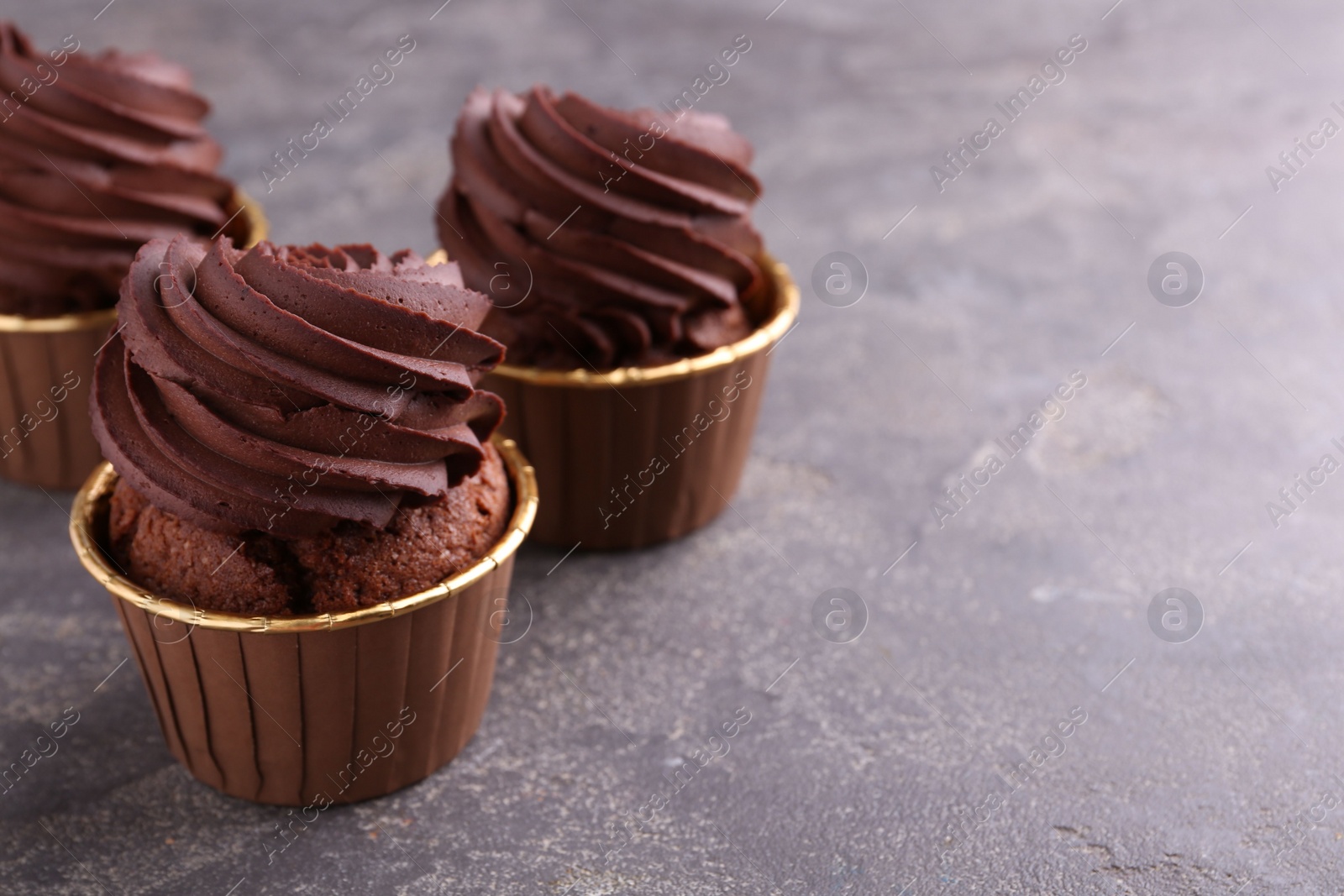 Photo of Delicious chocolate cupcakes on grey textured table, closeup. Space for text