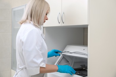 Gynecologist putting stainless forceps into sterile storage chamber in clinic