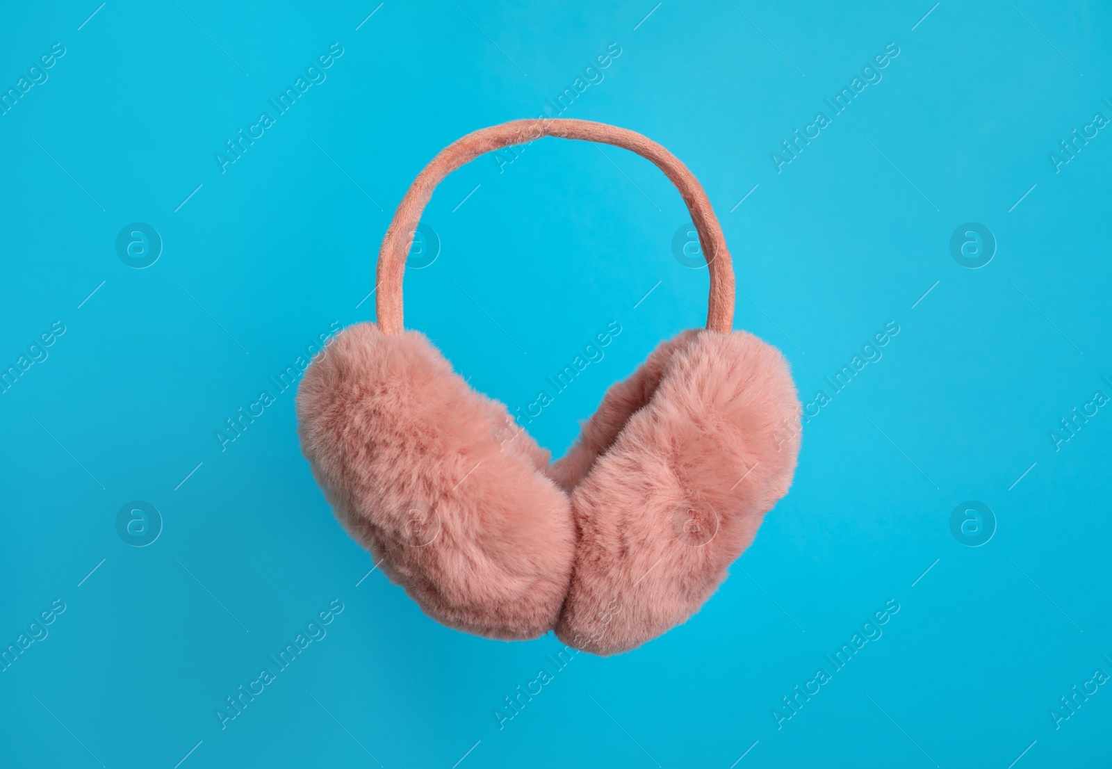 Photo of Stylish winter earmuffs on light blue background