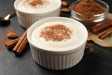 Photo of Delicious semolina pudding with cinnamon on black table