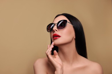 Photo of Attractive woman in fashionable sunglasses against beige background. Space for text