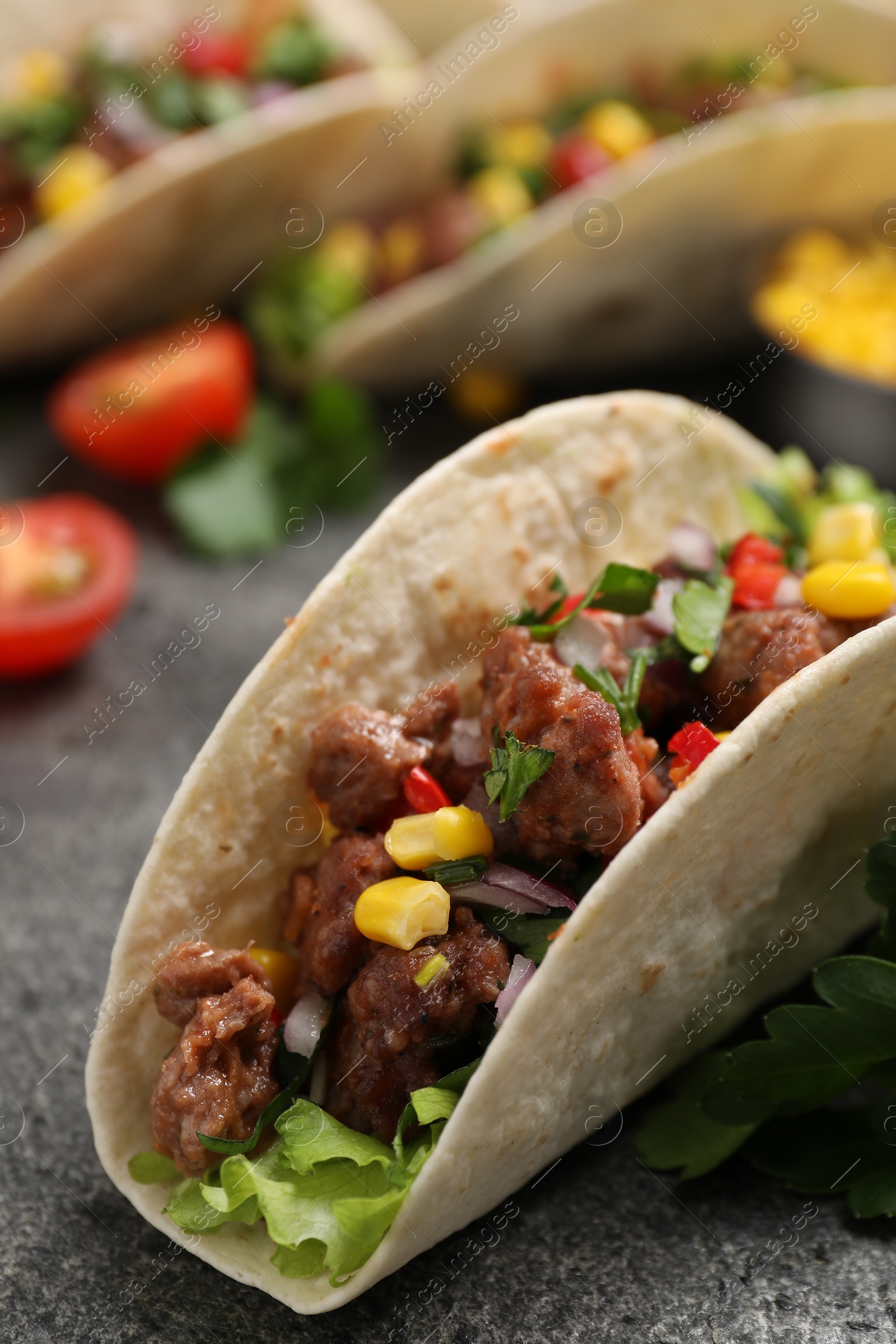 Photo of Delicious taco with meat and vegetables on gray textured table, closeup