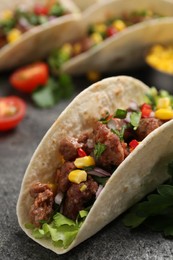 Photo of Delicious taco with meat and vegetables on gray textured table, closeup