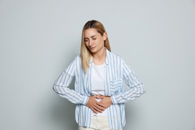 Photo of Young woman suffering from menstrual pain on light grey background