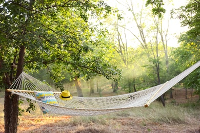 Photo of Comfortable net hammock and hat at green garden