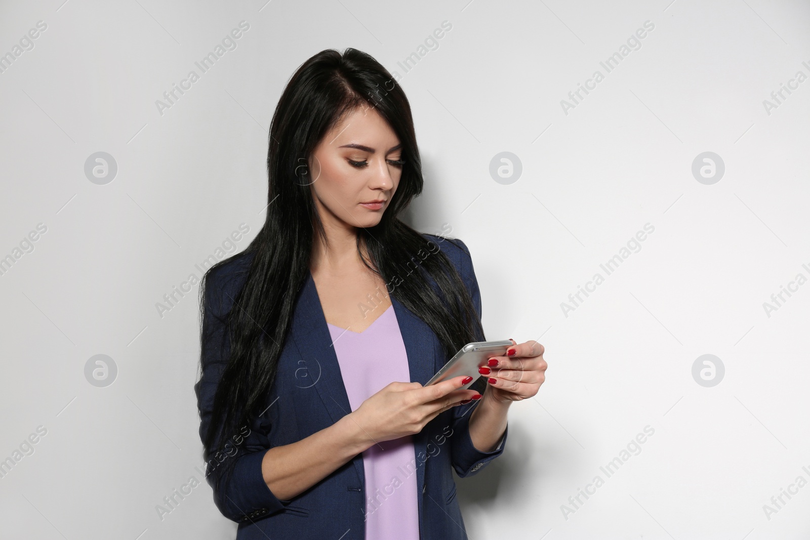 Photo of Portrait of stylish businesswoman using smartphone on light background. Space for text