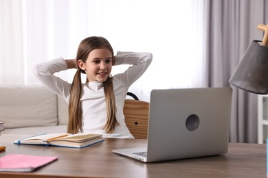 E-learning. Cute girl using laptop during online lesson at table indoors