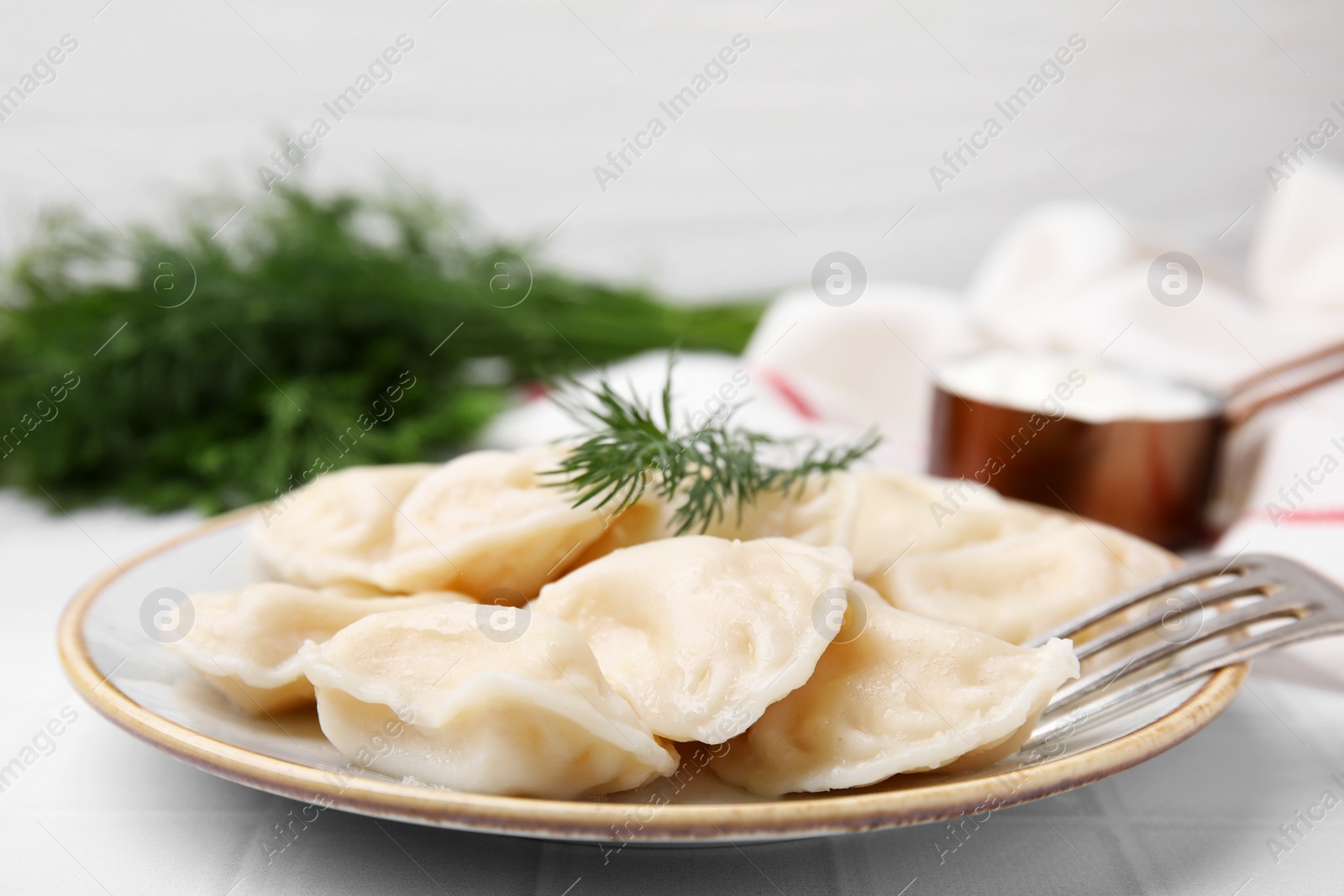 Photo of Cooked dumplings (varenyky) with tasty filling and dill on white table, closeup