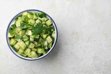 Photo of Bowl of delicious cucumber salad on light table, top view. Space for text