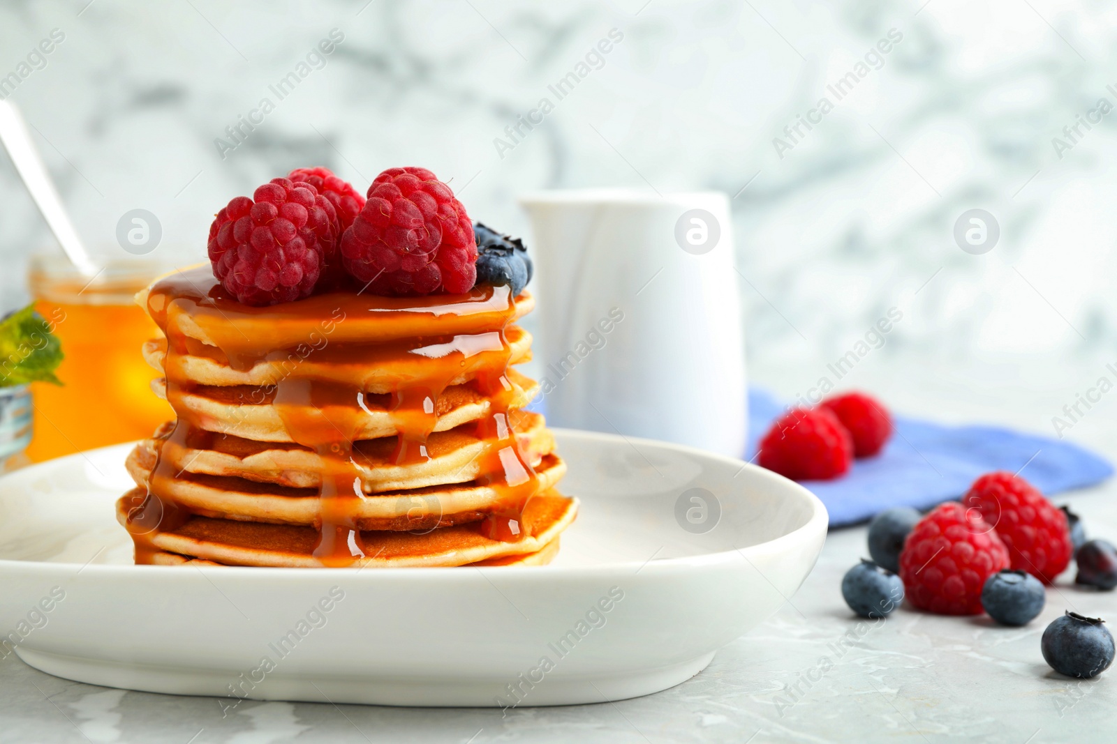 Photo of Delicious pancakes with fresh berries and syrup on grey table