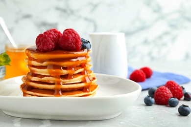 Photo of Delicious pancakes with fresh berries and syrup on grey table