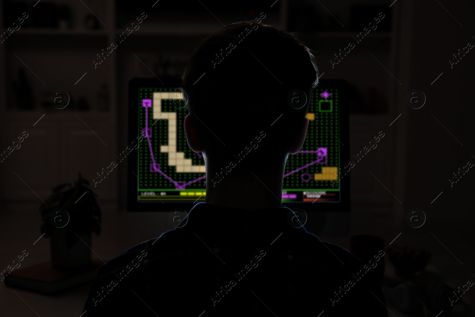 Image of Gaming disorder. Teenager playing on computer in darkness, back view