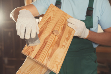 Photo of Professional carpenter polishing wooden drawer in workshop, closeup