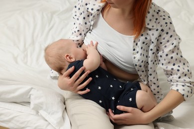 Mother breastfeeding her baby on bed, closeup