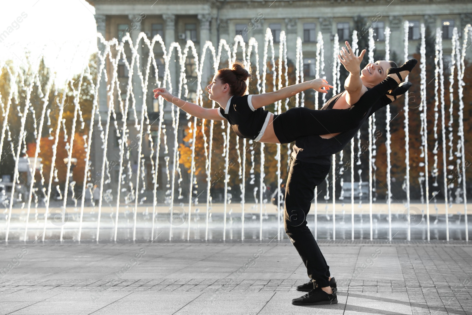 Photo of Beautiful young couple practicing dance moves near fountain outdoors