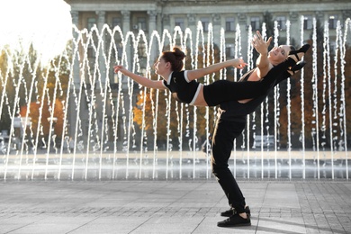 Beautiful young couple practicing dance moves near fountain outdoors