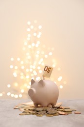 Piggy bank with euro banknote and coins on grey table against blurred lights, space for text