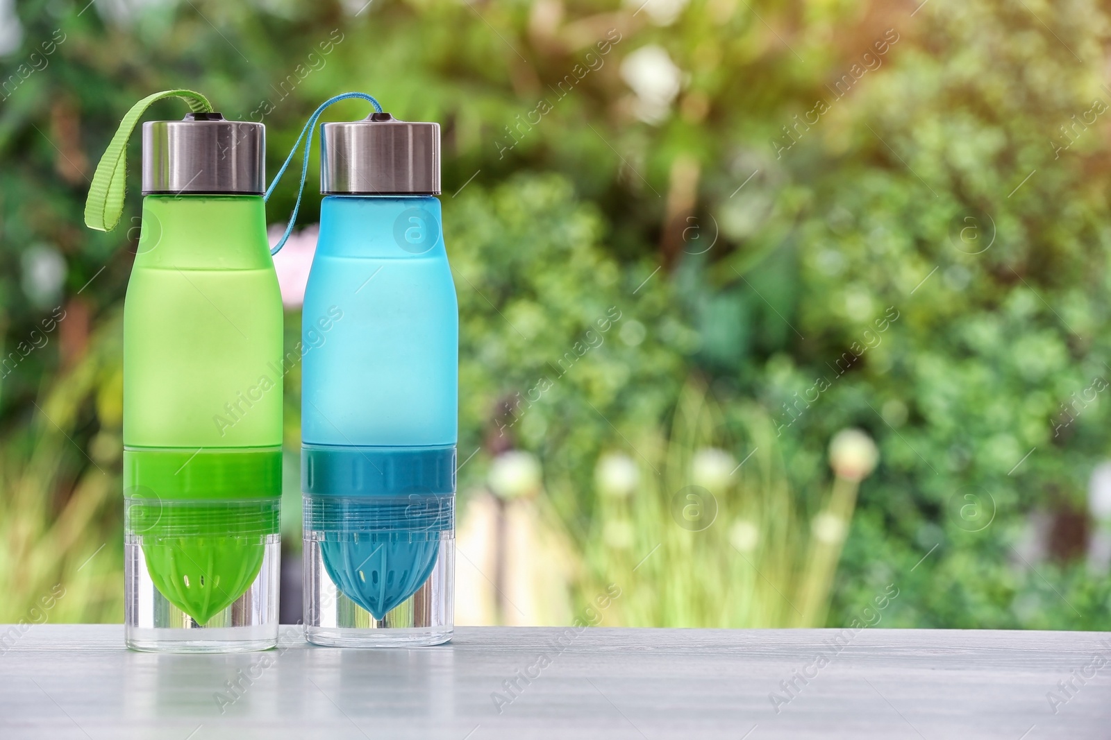 Photo of Sports water bottles on table against blurred background. Space for text