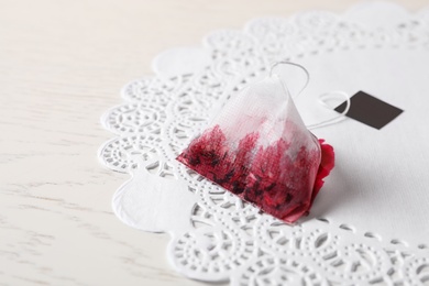 Used pyramid tea bag on white wooden table, closeup. Space for text