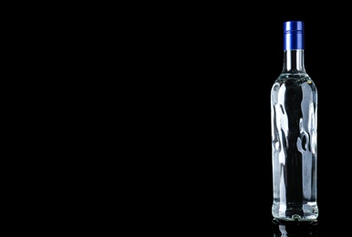 Photo of Bottle of vodka on black background. Space for text