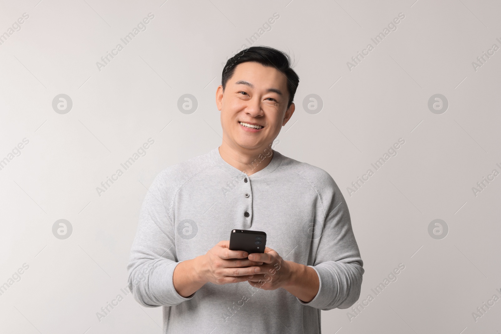 Photo of Portrait of happy man with smartphone on light background