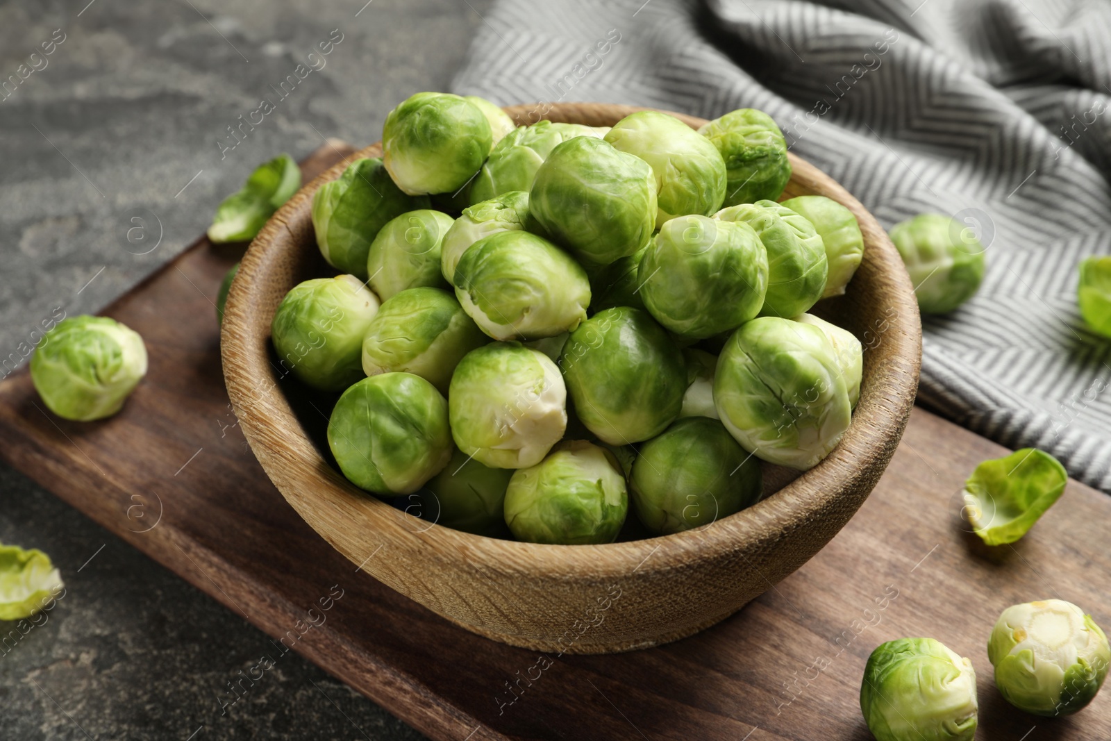 Photo of Board with bowl of Brussels sprouts on grey table