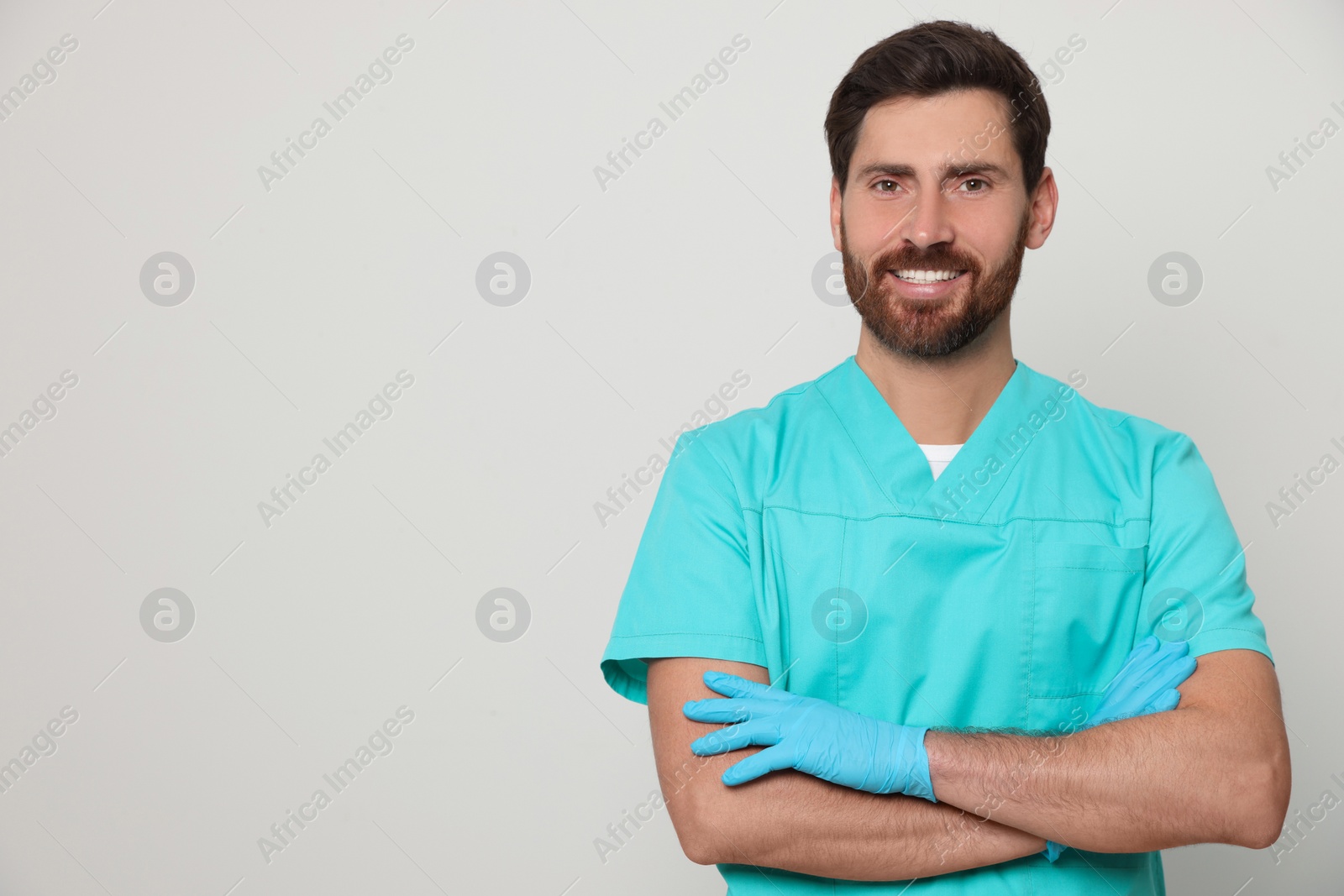 Photo of Happy nurse in medical uniform on white background, space for text