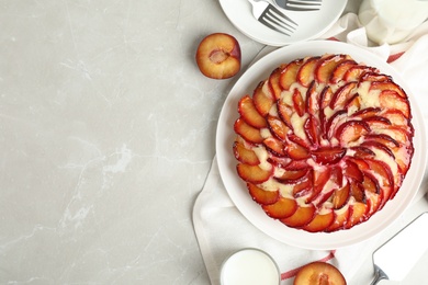 Photo of Delicious cake with plums on light marble table, flat lay. Space for text