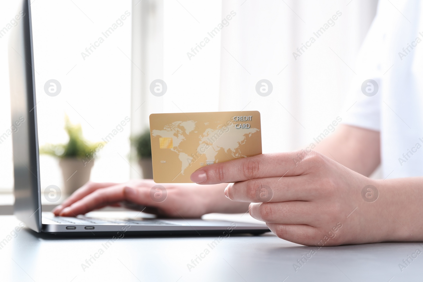 Photo of Online payment. Woman with laptop and credit card at white table, closeup