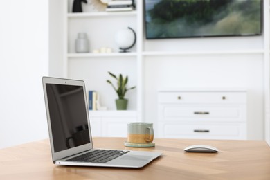 Interior design. Cosy workplace with laptop and cup on wooden table near tv area