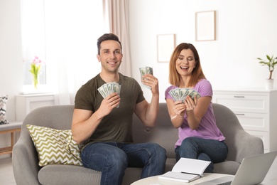 Couple with money on sofa in living room