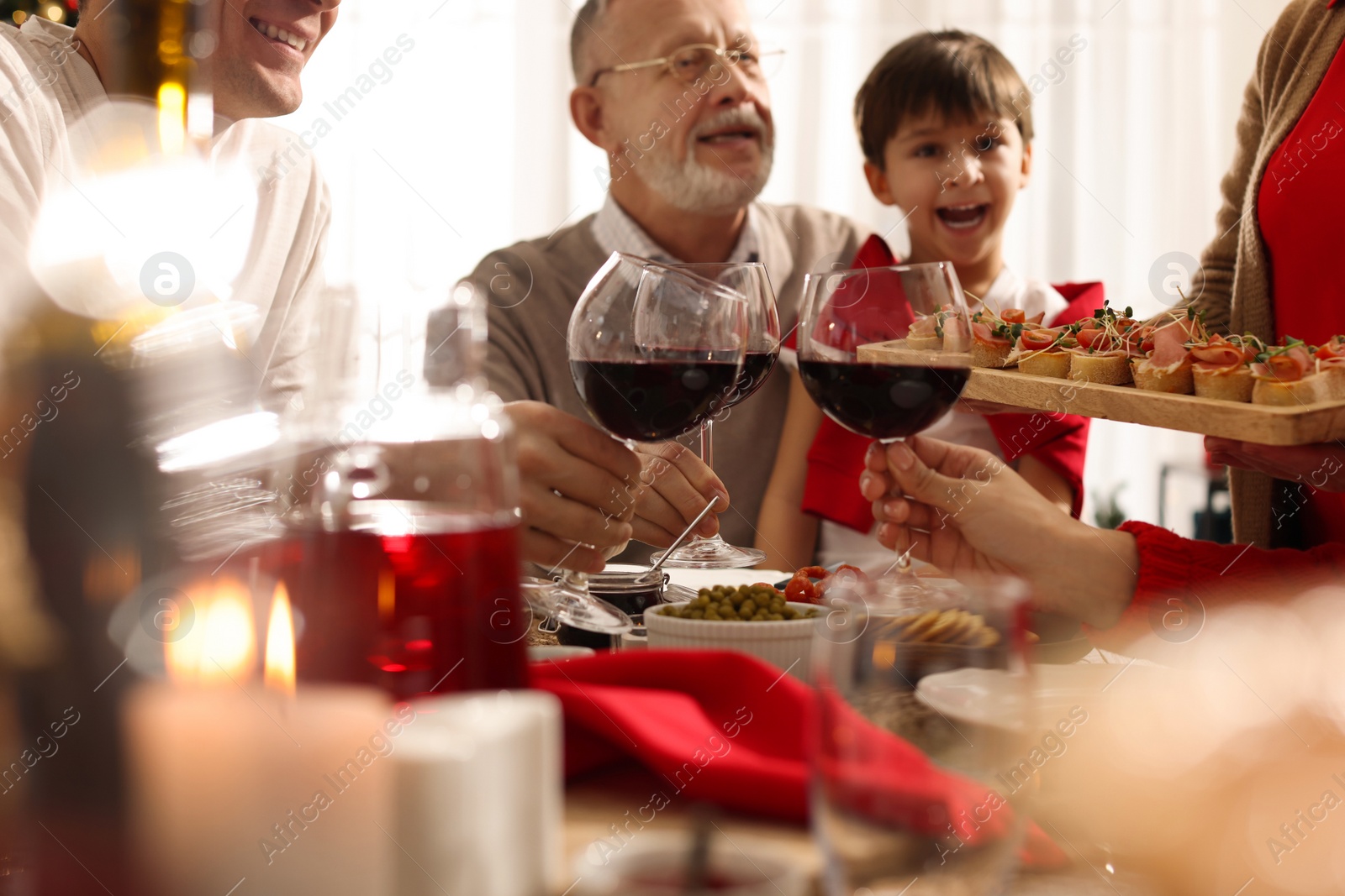 Photo of Family clinking glasses of wine at festive dinner, focus on hands. Christmas celebration