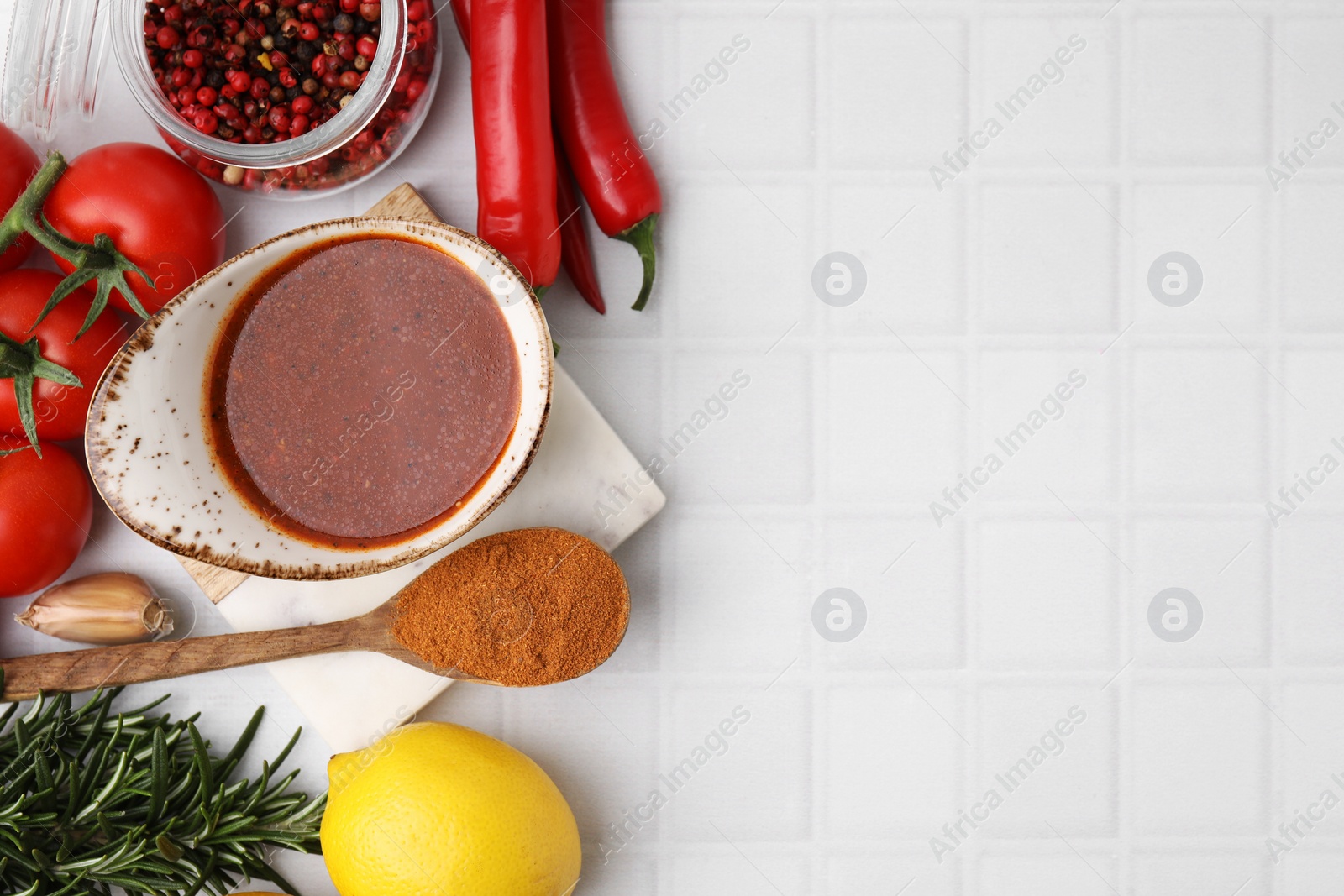 Photo of Fresh marinade and different ingredients on white tiled table, flat lay. Space for text