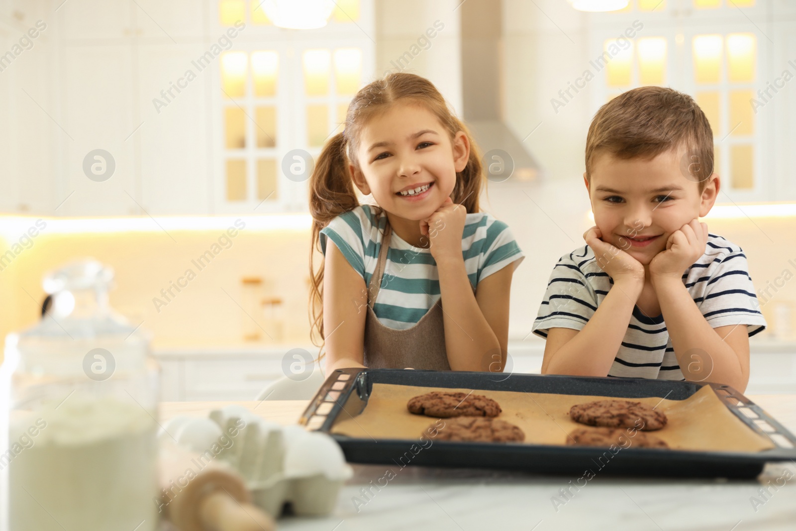 Photo of Cute little children with fresh delicious cookies in kitchen. Cooking together