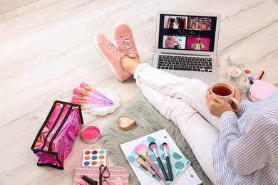 Photo of Beauty blogger with laptop and cosmetics sitting on floor, closeup