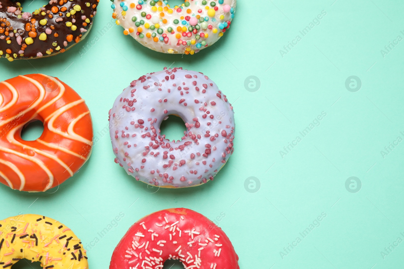 Photo of Delicious glazed donuts on turquoise background, flat lay. Space for text
