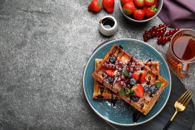 Photo of Delicious Belgian waffles with berries served on grey table, flat lay. Space for text
