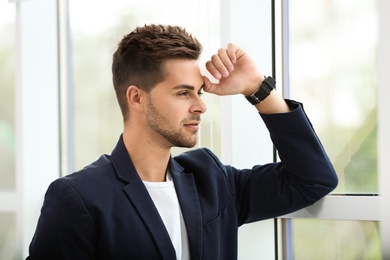 Photo of Portrait of handsome young man looking out window indoors